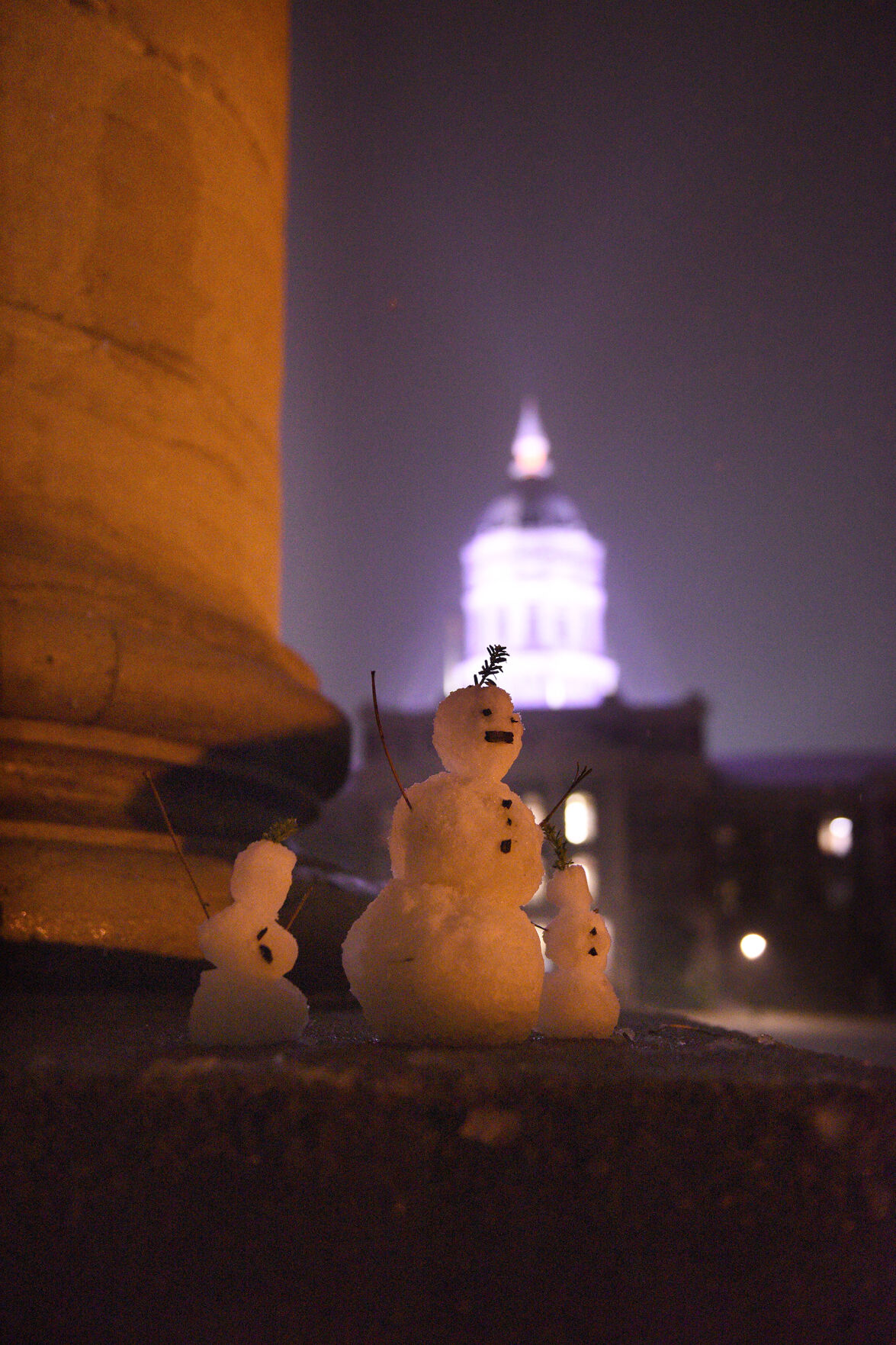 Snowpeople sit on one of the columns
